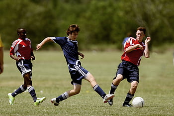 Teenage soccer players in action during an outdoor match showcasing skill and competition. HD wallpaper