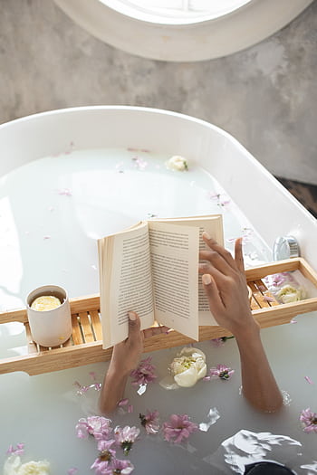 A tranquil scene of relaxation, reading a book in a flower-filled bathtub. HD phone wallpaper