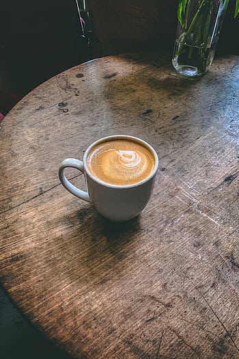A steaming latte with art on a rustic wooden table creates a cozy morning ambiance. HD phone wallpaper