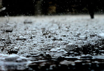 Detailed close-up of raindrops on a surface, capturing the essence of a heavy rain shower. HD wallpaper