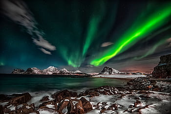 Captivating view of the Northern Lights over snow-covered Lofoten Islands at night. HD wallpaper