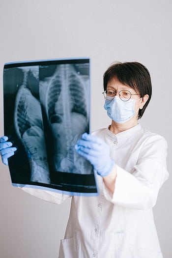 Medical professional in PPE examining chest X-ray results for diagnosis. HD phone wallpaper