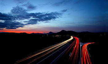 Long exposure of highway light streaks at twilight near Lovosice, Czechia, with a scenic mountain backdrop. HD wallpaper