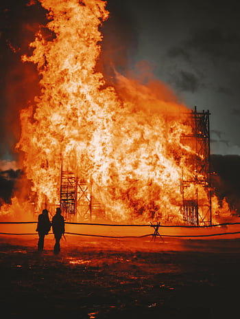 Silhouettes watching a large structure fire blaze against the night sky. HD phone wallpaper