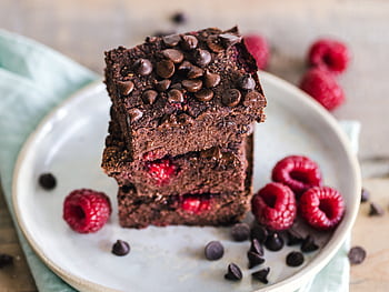 Close-up of deliciously indulgent chocolate raspberry brownies stacked on a ceramic plate with fresh raspberries. HD wallpaper