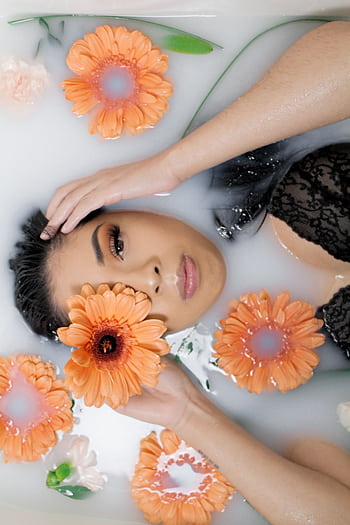 Woman in a black lace top relaxing in a milk bath with orange flowers. HD phone wallpaper