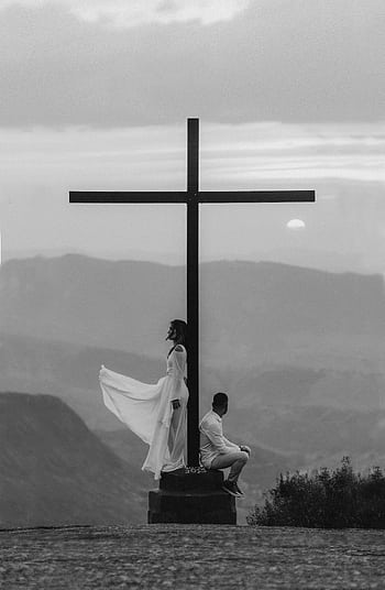 A serene moment of spiritual reflection by a cross at sunset with a dramatic sky in the background. HD phone wallpaper