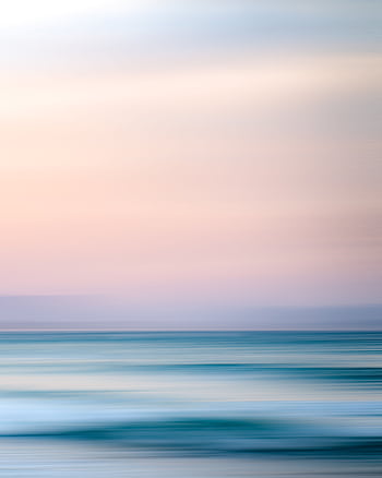 A serene seascape with pastel sky and calm ocean waves at sunset, perfect for tranquil backgrounds. HD phone wallpaper