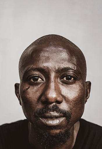 Intense close-up portrait of an African man with a serious expression and facial hair. HD phone wallpaper