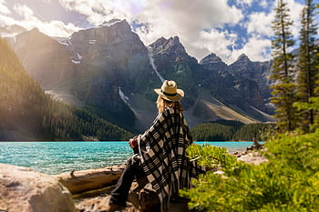 Woman in a poncho gazing at Moraine Lake surrounded by mountains, Alberta, Canada. HD wallpaper