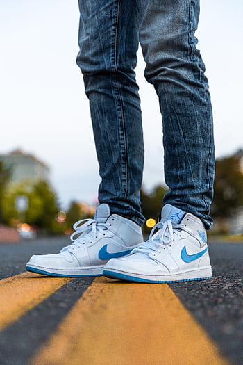 Stylish blue and white sneakers standing on a road with a vibrant urban background. HD phone wallpaper