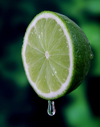 Macro shot of a juicy, fresh lime slice with a water droplet, highlighting its vibrant green color. HD phone wallpaper
