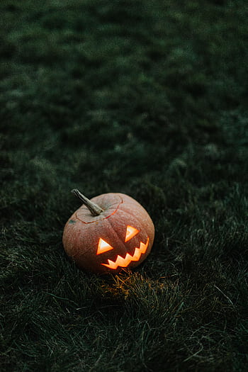A spooky carved pumpkin glowing in the dark, perfect for Halloween themes. HD phone wallpaper