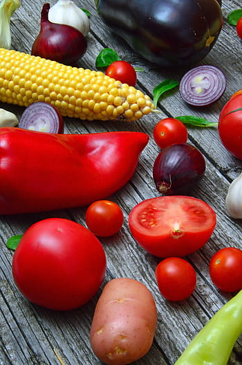 A vibrant assortment of fresh vegetables on a rustic wooden table, ready for cooking. HD phone wallpaper