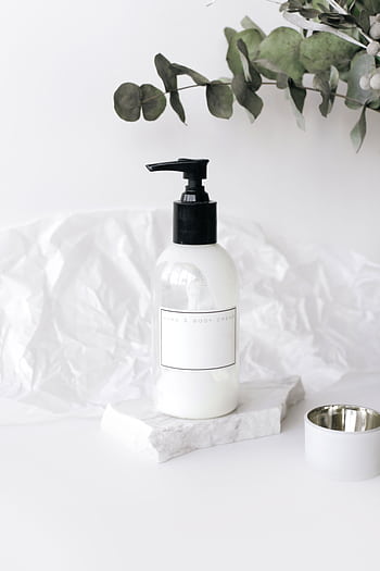 Elegant lotion bottle on marble with green leaves, perfect for skincare ads. HD phone wallpaper