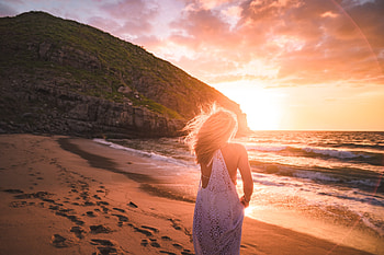 Woman in white gown walks across a hillside beach at sunset, coast, golden hour, girl, oceab, gold, woman, beach, sky, hillside, women, gown, sun, sunset, hill, sand, blonde, golden, alone, clouds HD wallpaper
