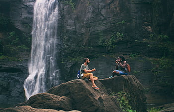 A serene moment captured by a waterfall in India with a couple enjoying nature's beauty together. HD wallpaper