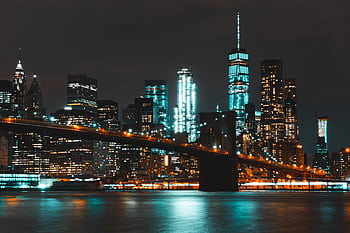 Captivating night skyline of New York City with Brooklyn Bridge and skyscraper reflections. HD wallpaper