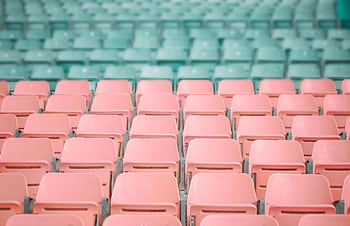 Empty pastel pink and mint green stadium seats, artistically arranged in rows. HD wallpaper