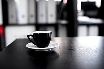 Black coffee cup on a wooden desk in an office setting. Minimalist and modern interior design vibe. HD wallpaper