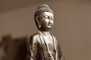 Close-up of a serene silver Buddha statue, highlighting Buddhist spirituality and art. HD wallpaper