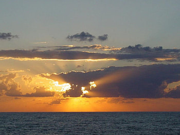 Sunset behind clouds., clouds, rays, water, sunset HD wallpaper