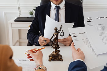 Legal professionals reviewing divorce documents in a law office with a Lady Justice statue. HD wallpaper