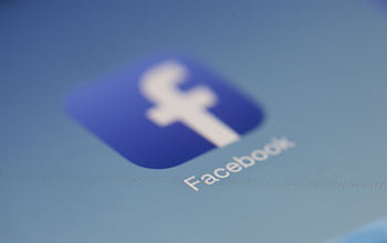 Close-up view of the Facebook app logo on a digital screen with blurred background. HD wallpaper