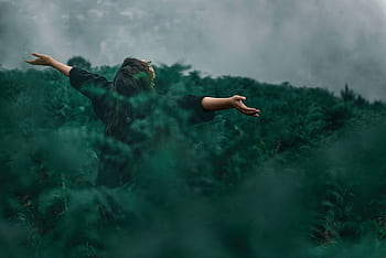 A woman with open arms enjoying dom in a foggy green landscape. HD wallpaper