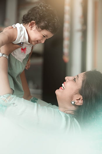 A joyful mother and child sharing a tender moment together indoors, radiating happiness. HD phone wallpaper