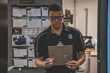 A serious worker in a warehouse checks documents on a clipboard, planning and logistics. HD wallpaper