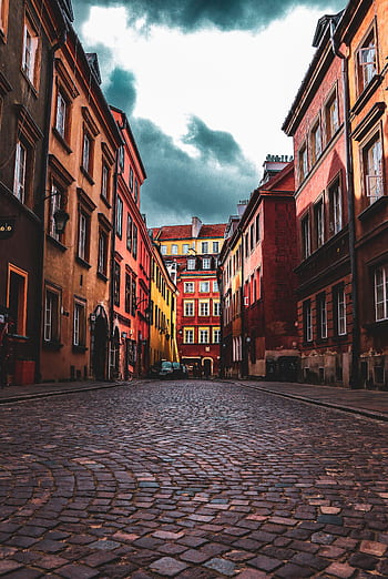 Dramatic view of cobblestone street in Warsaw's Old Town, showcasing colorful historic architecture. HD phone wallpaper