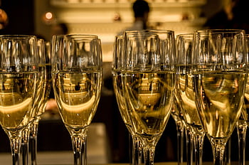 Array of filled champagne glasses in a luxurious indoor setting, ready for celebration. HD wallpaper