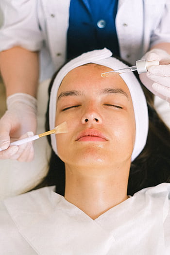 Young woman receiving a relaxing facial treatment in a modern spa setting, promoting relaxation and rejuvenation. HD phone wallpaper