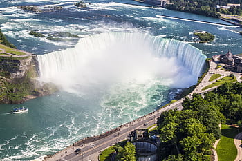 Stunning aerial shot of Niagara Falls with a boat tour and lush greenery on a sunny summer day. HD wallpaper