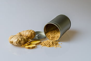 Close-up of fresh ginger root with sliced pieces and ginger powder spilled from a metal container. HD wallpaper