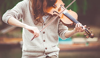 Close-up of a violinist playing outdoors in warm tones, capturing the essence of live music. HD wallpaper