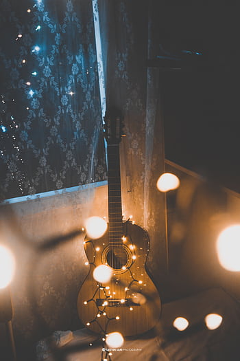 Acoustic guitar adorned with warm string lights creating a cozy indoor atmosphere. HD phone wallpaper