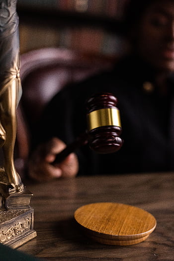 Close-up of a judge holding a gavel, symbolizing justice and law in a courtroom setting. HD phone wallpaper
