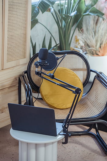 A cozy podcast recording setup featuring a mic, laptop, and stylish interior, ideal for content creators. HD phone wallpaper