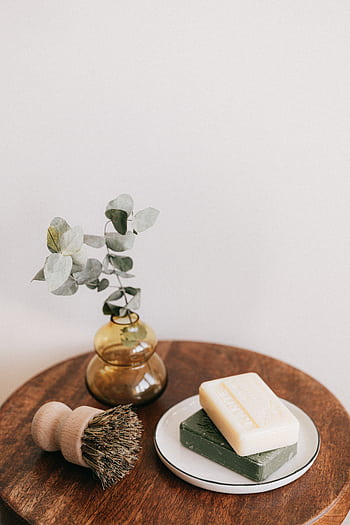 Elegant arrangement of soaps and a vase on a wooden table, perfect for a spa or skincare theme. HD phone wallpaper