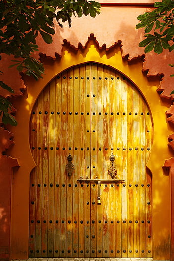 Traditional wooden gate with vibrant orange arches illuminated by sunlight. Perfect for travel and architecture themes. HD phone wallpaper