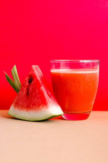 Refreshing watermelon juice and slice against a vibrant red background, perfect for summer vibes. HD phone wallpaper