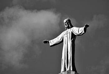 Black and white of a Jesus Christ statue reaching out against a cloudy sky. HD wallpaper