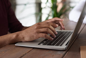 Hands of a person typing on a laptop keyboard indoors, ideal for remote work and lancing themes. HD wallpaper