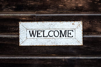 A rustic vintage-style 'Welcome' sign on a wooden wall creating a warm and inviting atmosphere. HD wallpaper