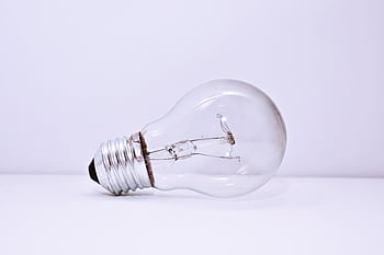 A clear incandescent light bulb lying on a simple white background, showcasing minimalism. HD wallpaper