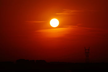 A striking sunset casting a golden glow over a silhouetted landscape with a power line tower. HD wallpaper