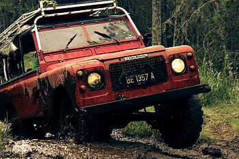 A rugged vintage Land Rover conquers a muddy trail, showcasing off-road capabilities and adventure spirit. HD wallpaper