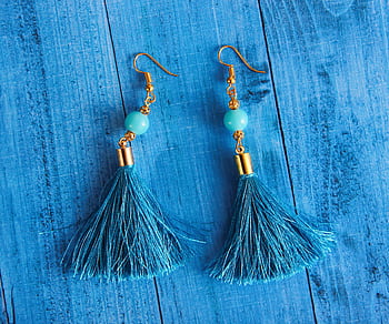 Stylish blue tassel earrings with gold accents displayed on a wooden surface. HD wallpaper